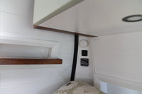 Flush mounted wireless charger on a white vertical camper wall