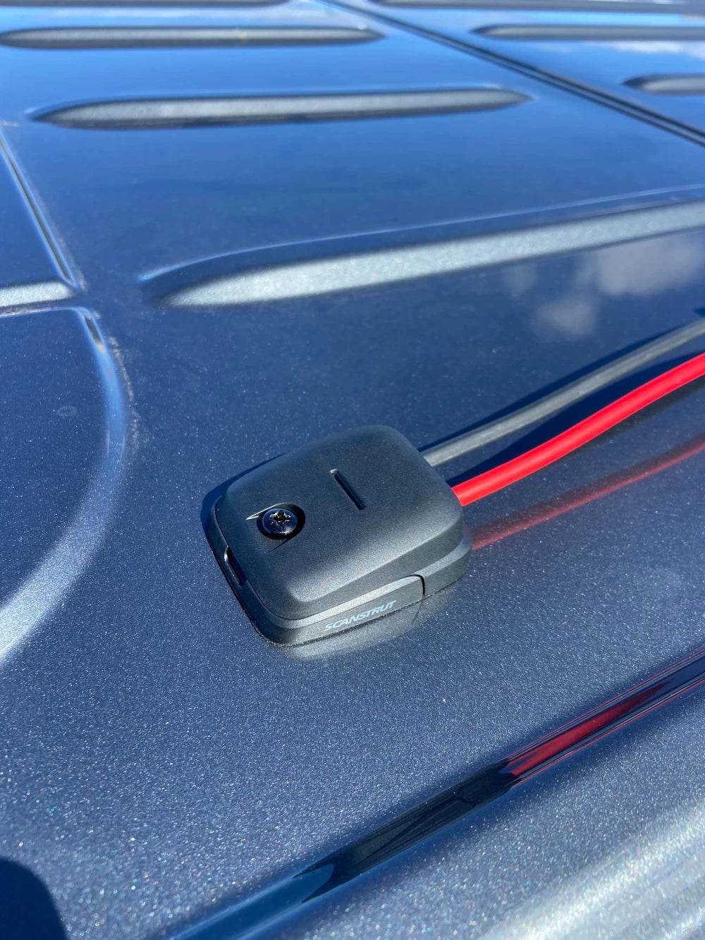 Cable seal routing red and black power cables through a vehicle roof