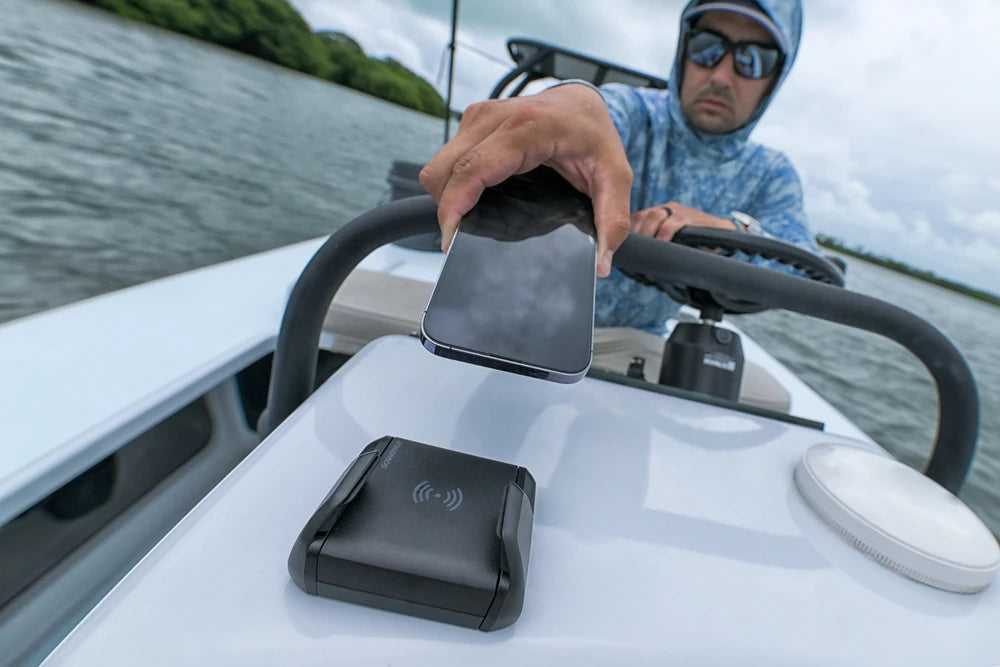 User docking a smartphone into a waterproof wireless charger on a boat dash