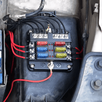 Automotive fuse block installed in engine bay with connected wiring and inserted blade fuses