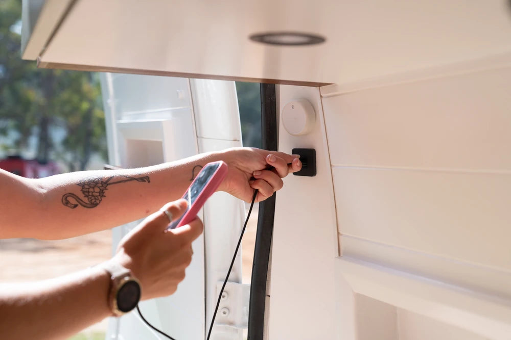 User plugging a charging cable into a Scanstrut TILE socket in a van conversion