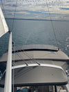 Three fixed solar panels mounted on the grey canvas bimini top of a sailboat moving through water