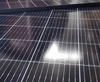 Close-up angled view of solar panel surface showing grid lines on black cells and tempered glass texture