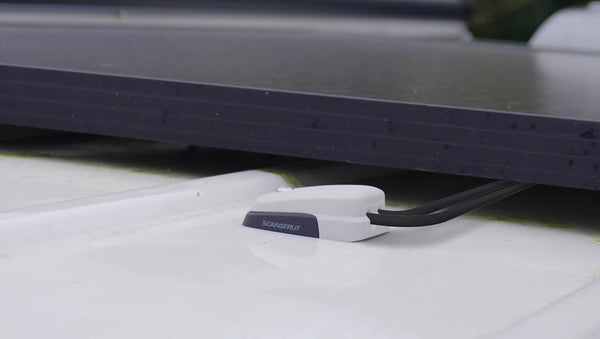 Low profile grey cable seal installed on a textured white roof surface