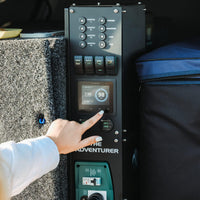 Close-up of a hand operating the Simarine touch screen battery monitor in a canopy