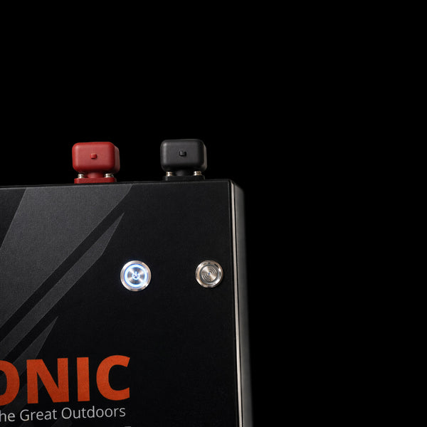 Close-up of illuminated stainless steel power button and status indicator on the black battery face