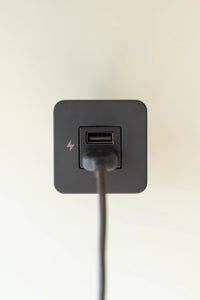 Close-up of a black USB-A charging socket with a power cable plugged in
