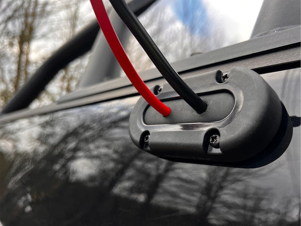 Black and red cables passing through a Scanstrut seal on a black vehicle roof