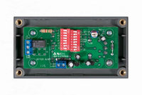 Internal view of battery alarm showing PCB with DIP switches and terminal blocks