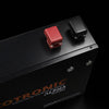 High-angle close-up of red and black M8 battery terminals with protective covers on top of black metal casing