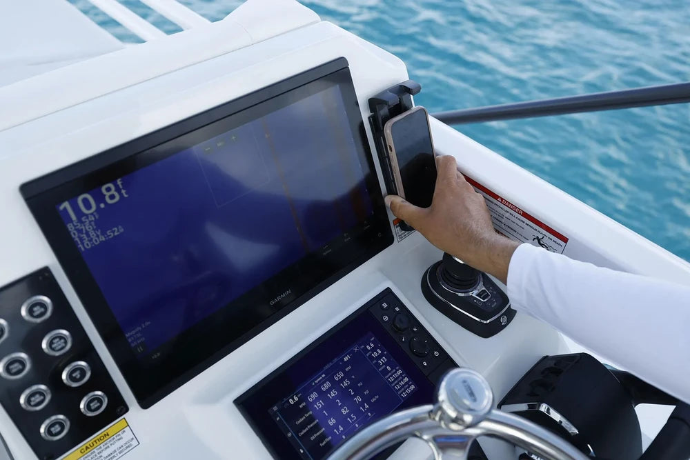 Hand placing a phone into the charger on a marine dashboard installation