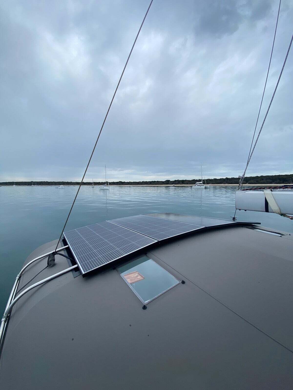 Two rectangular solar panels installed flat on the curved cabin roof of a boat anchored in calm water