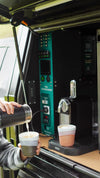 Person pouring coffee next to a canopy power system installed in a 4WD vehicle