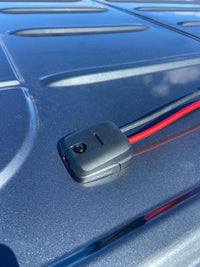 Cable seal routing red and black power cables through a vehicle roof
