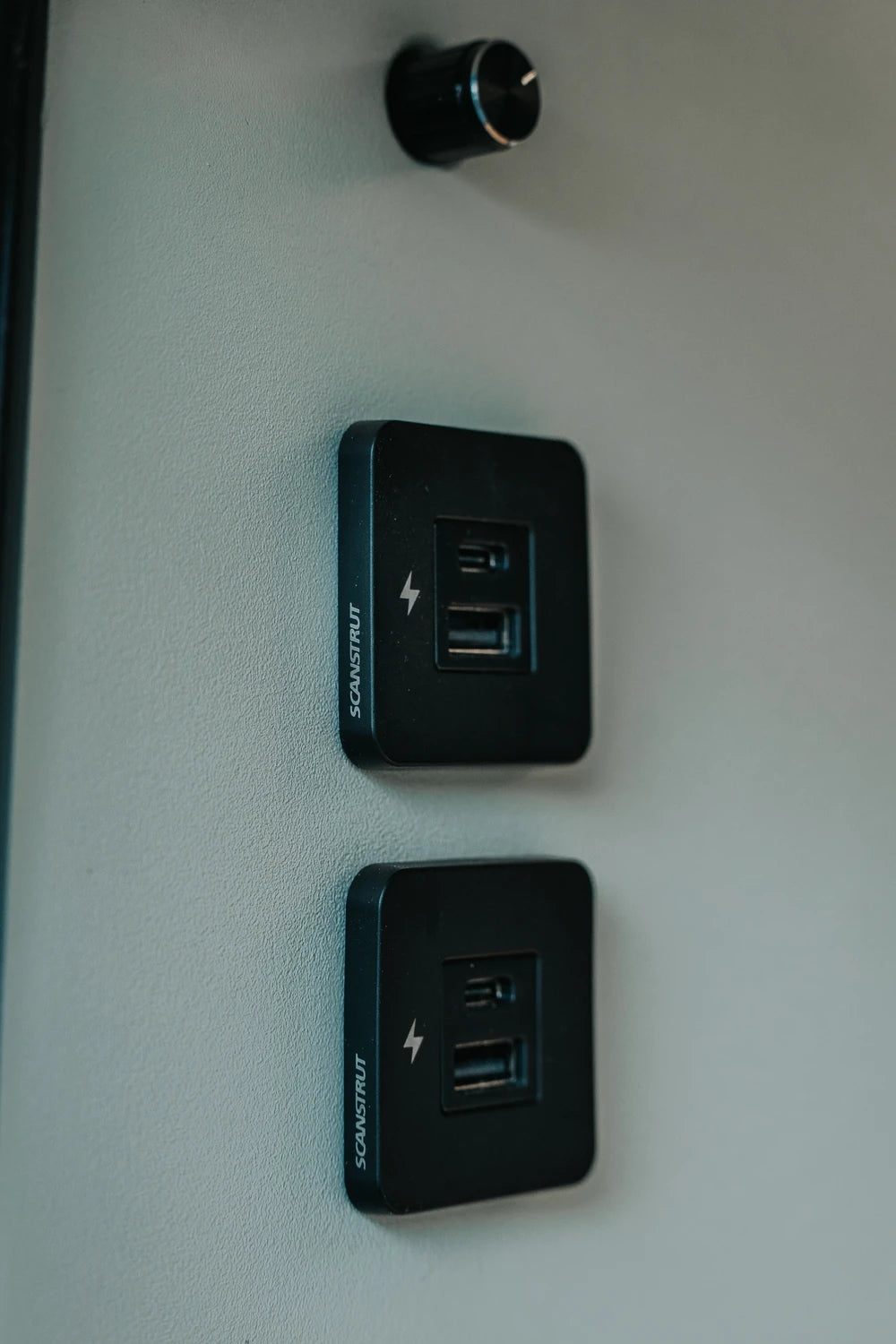 Two black Scanstrut TILE USB sockets mounted vertically on a campervan interior wall