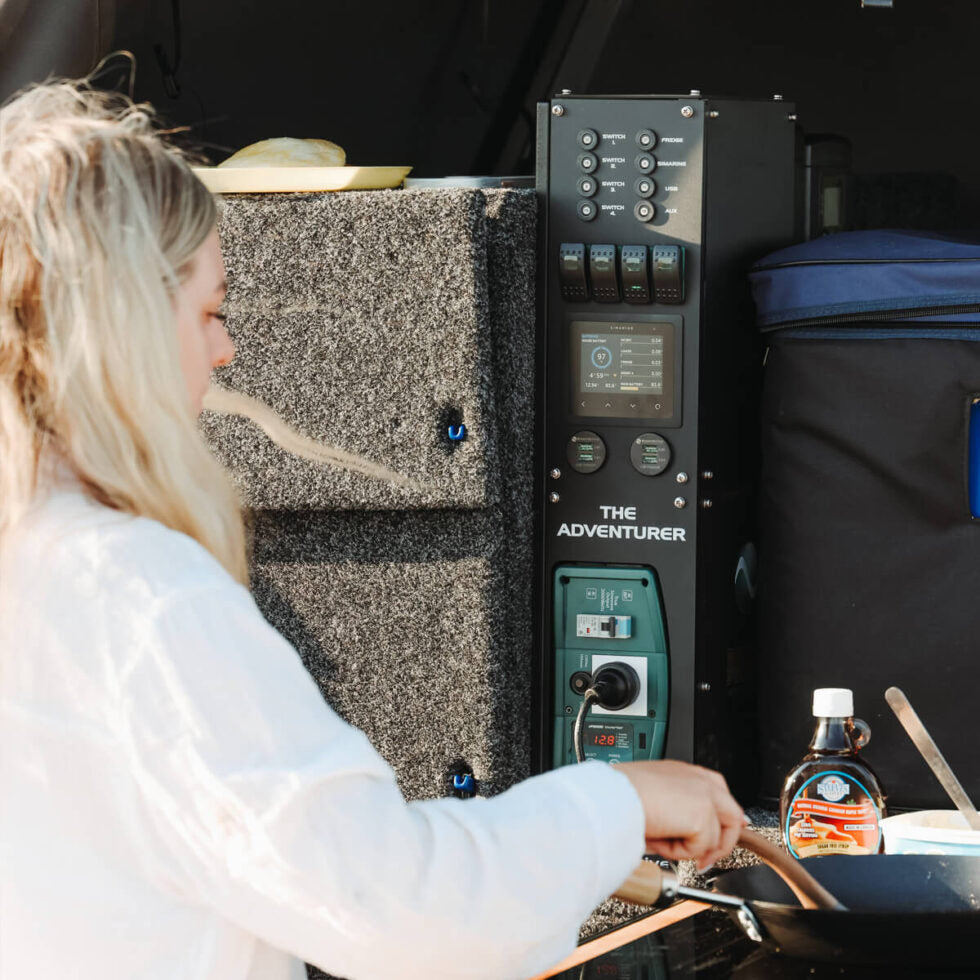 Woman cooking at the back of a 4x4 canopy featuring the Adventurer power system