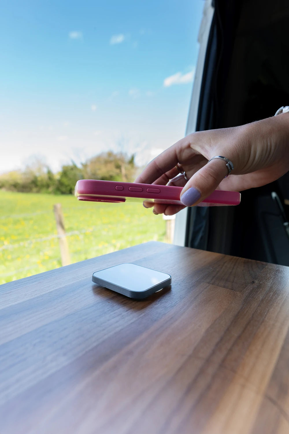 User placing a phone on the magnetic charger mounted to a timber surface