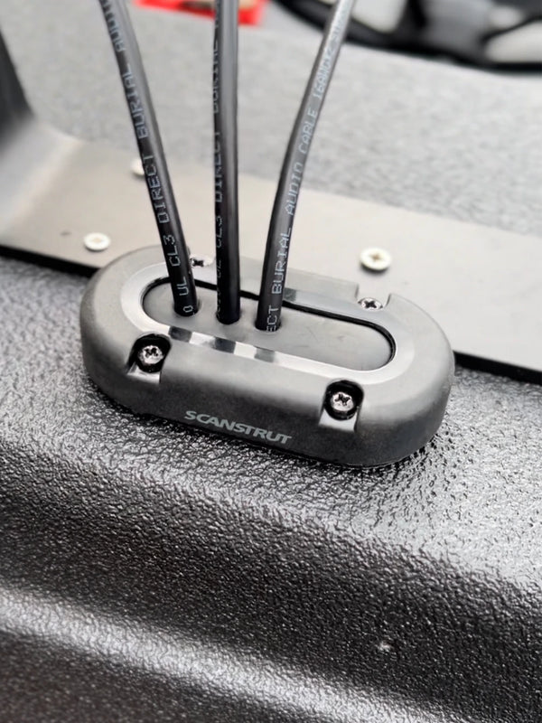 Three black cables entering a vertical Scanstrut seal on a textured black surface