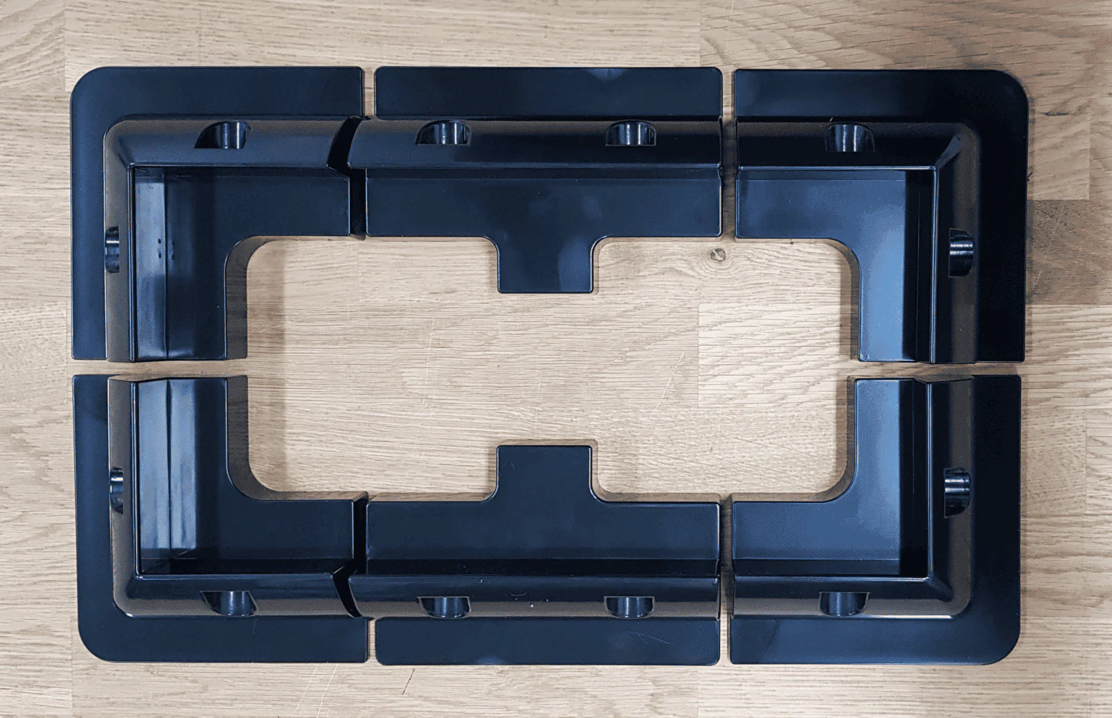 Overhead layout view of four corner brackets and two mid brackets arranged on a wooden surface