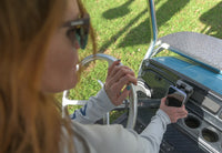 Hand placing a smartphone into the adjustable waterproof wireless charger on a utility vehicle
