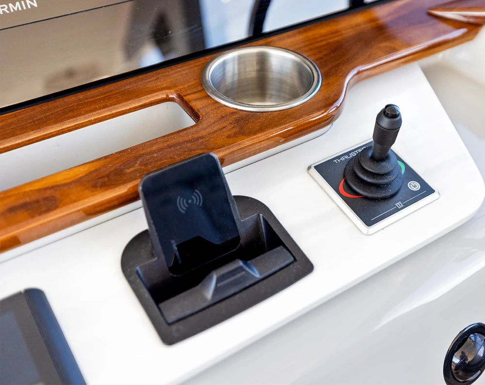 Integrated Aura wireless charger on a white marine dashboard with wood trim