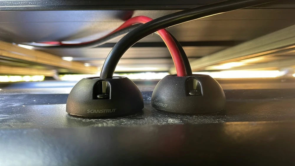 Low-angle view of two black vertical cable seals installed on a flat surface with cables