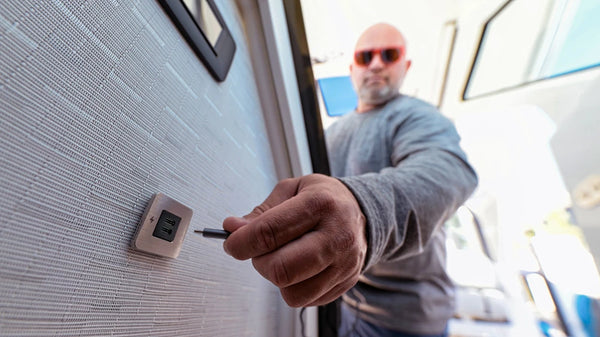 Hand plugging a USB-C cable into the installed brushed stainless socket in a boat cabin