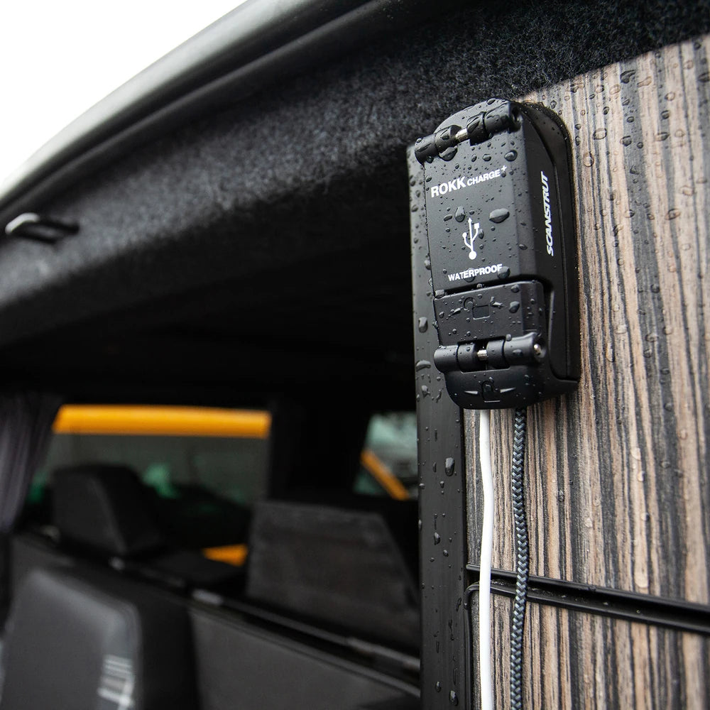 Waterproof USB socket mounted on timber-look wall with water spray